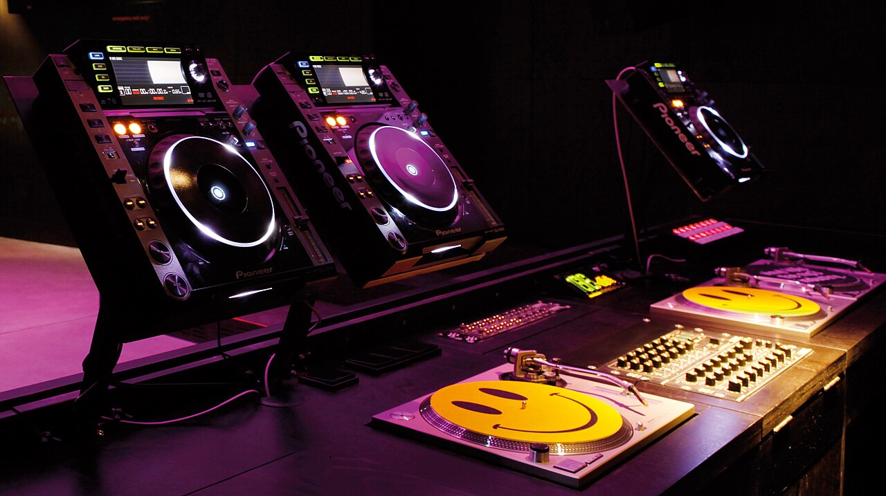 Trois lecteurs CDJ et deux platines dans une cabine de DJ